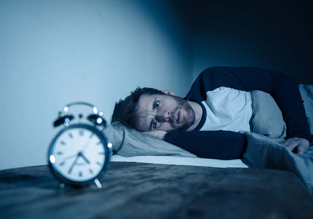 man looking at the clock while having trouble sleeping